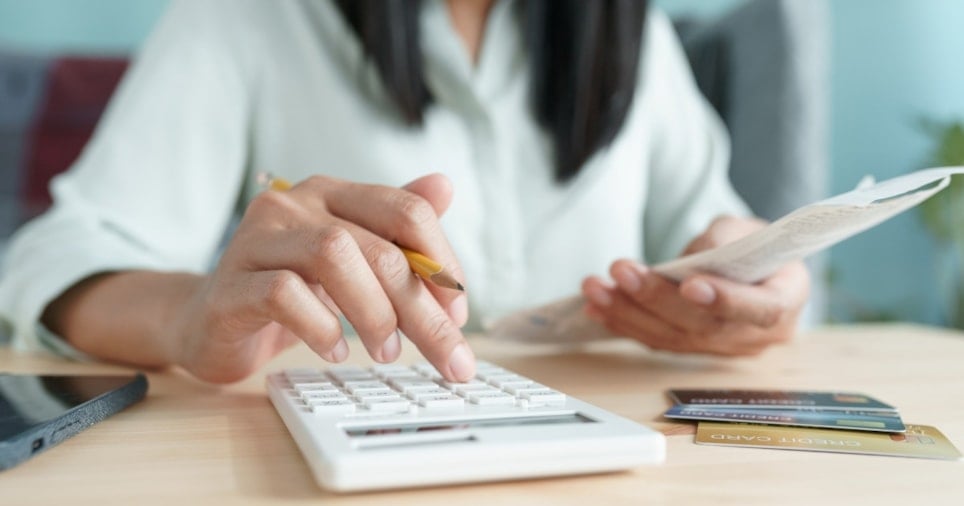 Kvinne sitter med kalkulator og regninger.
