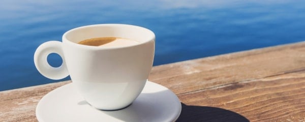 En kaffekopp på bryggen ved sjøen. Foto.