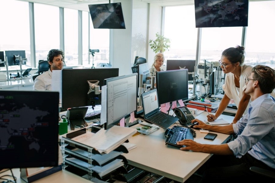 Personer som samarbeider på kontor foran pc-skjermer. Foto.